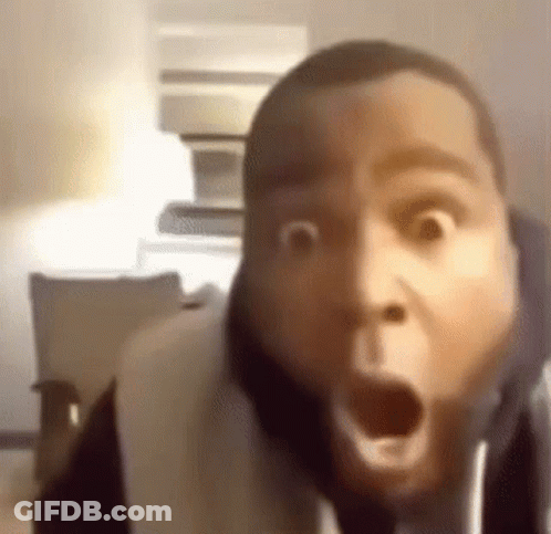 A Man Is Making A Funny Face With His Mouth Open While Sitting On A Couch . GIF