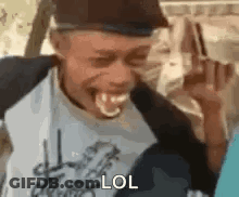 A Man Is Making A Funny Face With His Tongue Out While Wearing A Hat And Smiling . GIF