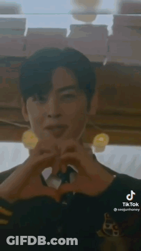 A Man Is Making A Heart Shape With His Hands In A Restaurant . GIF