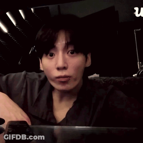 A Man Is Making A Heart Shape With His Hands In Front Of A Sign That Says U GIF