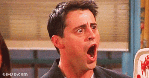 A Man Is Making A Surprised Face With His Mouth Open In A Room . GIF