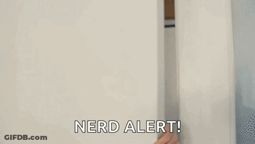 A Man Is Peeking Out From Behind A White Wall And Saying `` Nerd Alert '' . GIF