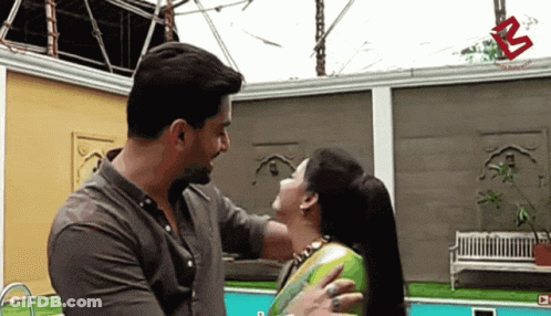 A Man Is Petting A Woman 'S Neck In Front Of A Swimming Pool GIF