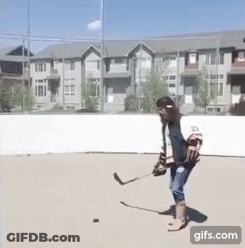 A Man Is Playing A Game Of Ice Hockey On A Concrete Rink . GIF