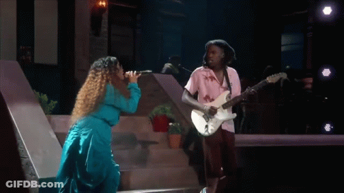A Man Is Playing A Guitar And A Woman Is Singing . GIF