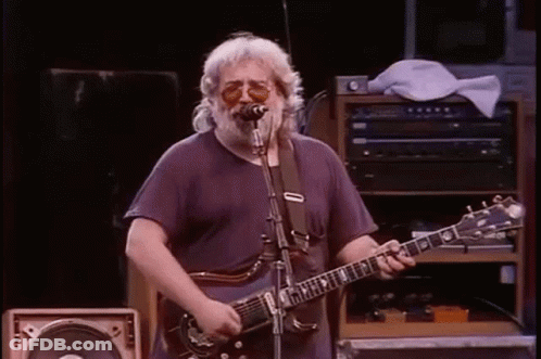 A Man Is Playing A Guitar And Singing Into A Microphone . GIF