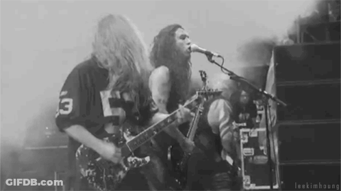 A Man Is Playing A Guitar And Singing Into A Microphone While Another Man Plays Drums . GIF