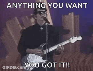 A Man Is Playing A Guitar And Singing Into A Microphone While Standing On A Stage . GIF