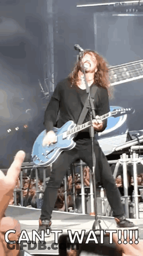 A Man Is Playing A Guitar And Singing Into A Microphone With The Words Can 'T Wait Written Below Him GIF