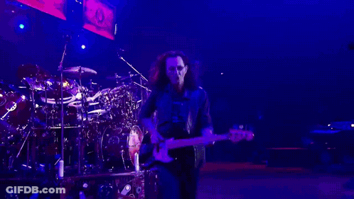 A Man Is Playing A Guitar In A Dark Room GIF