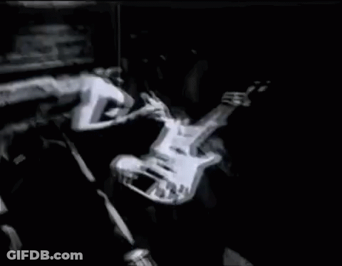 A Man Is Playing A Guitar In A Dark Room . GIF