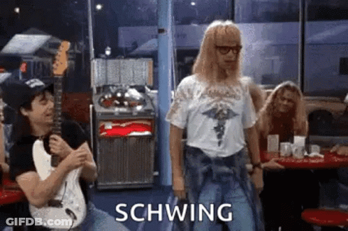 A Man Is Playing A Guitar In A Diner While Another Man Is Dancing . GIF