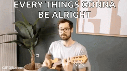 A Man Is Playing A Guitar In A Living Room With A Potted Plant . GIF