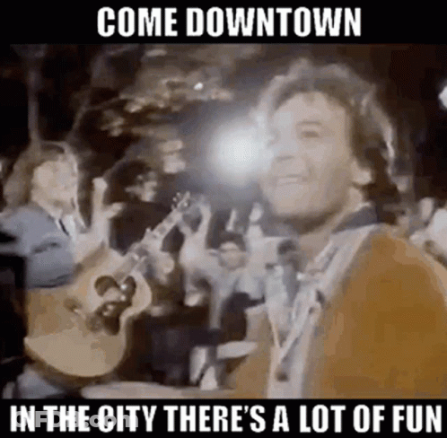 A Man Is Playing A Guitar In Front Of A Crowd Of People While Standing In Front Of A Crowd . GIF