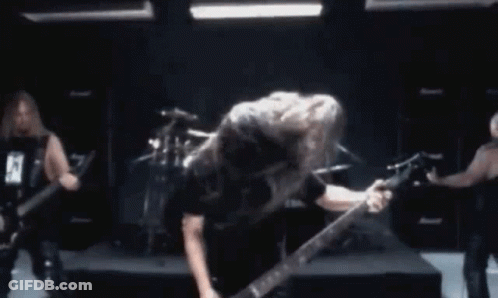 A Man Is Playing A Guitar In Front Of A Drum Set While Another Man Plays Drums GIF