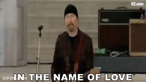 A Man Is Playing A Guitar In Front Of A Microphone And Singing . GIF