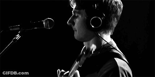 A Man Is Playing A Guitar In Front Of A Microphone In A Black And White Photo GIF