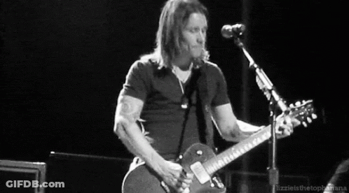 A Man Is Playing A Guitar In Front Of A Microphone . GIF