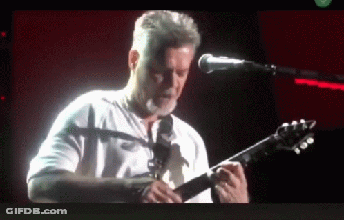 A Man Is Playing A Guitar In Front Of A Microphone GIF