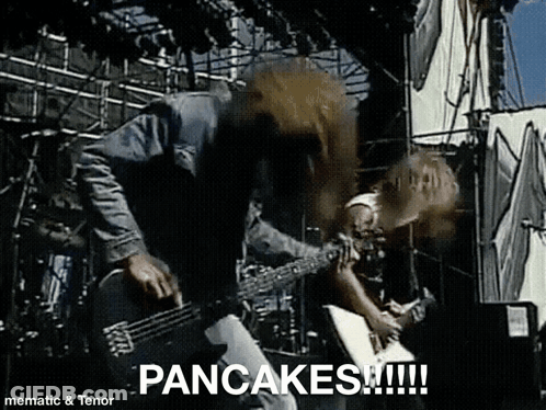 A Man Is Playing A Guitar On A Stage And The Words Pancakes Are On The Screen . GIF