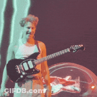 A Man Is Playing A Guitar On A Stage GIF