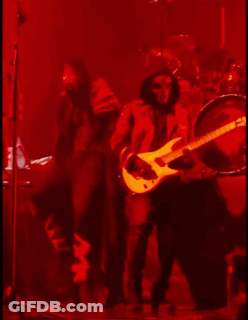 A Man Is Playing A Guitar On A Stage In A Dark Room GIF
