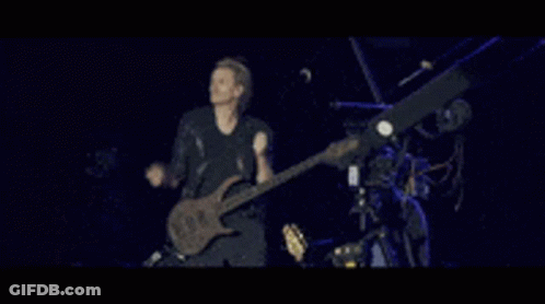 A Man Is Playing A Guitar On A Stage GIF