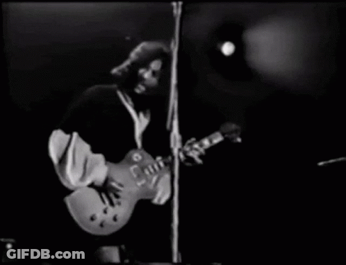 A Man Is Playing A Guitar On Stage In A Black And White Photo . GIF