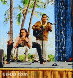 A Man Is Playing A Guitar While A Woman Sings On Stage GIF