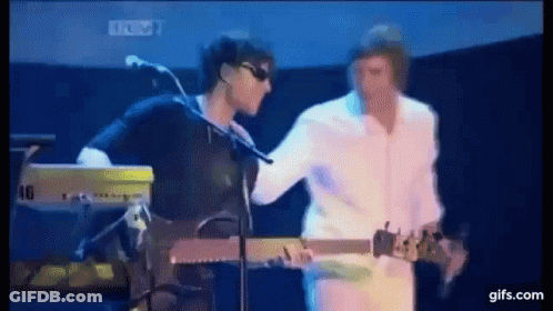 A Man Is Playing A Guitar While Another Man Is Playing A Keyboard On Stage . GIF