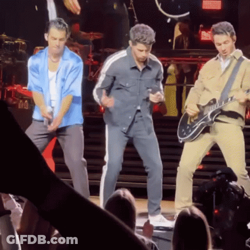 A Man Is Playing A Guitar While Another Man Is Singing On Stage GIF