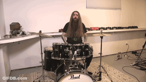 A Man Is Playing A Pearl Drum Set In A Room GIF