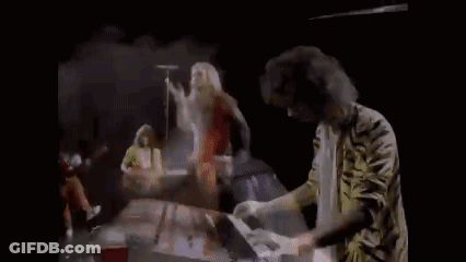 A Man Is Playing A Piano And Holding A Piece Of Paper In His Hands . GIF