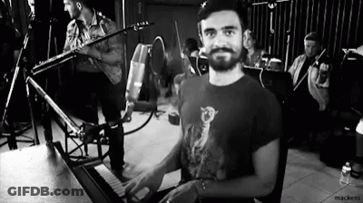 A Man Is Playing A Piano In A Black And White Photo While A Band Plays In The Background . GIF