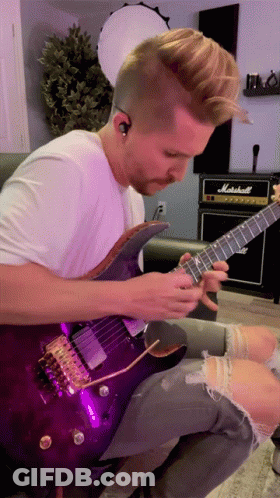 A Man Is Playing A Purple Guitar In Front Of A Marshall Amp GIF