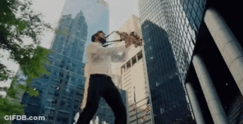 A Man Is Playing A Saxophone In Front Of A City Skyline GIF