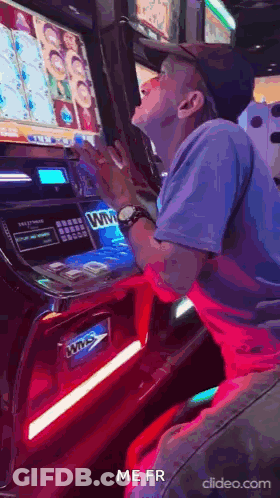 A Man Is Playing A Slot Machine In A Casino And Making A Funny Face . GIF