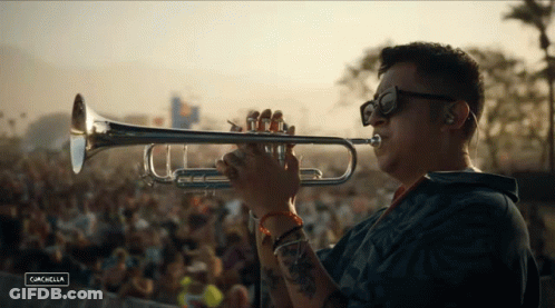 A Man Is Playing A Trumpet In Front Of A Crowd At A Music Festival Called Cancabella GIF