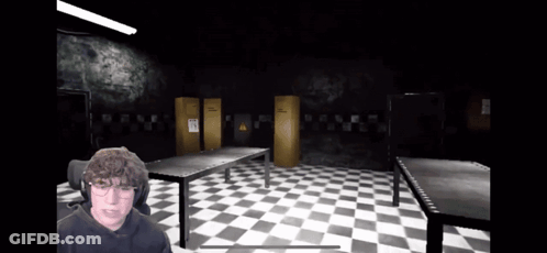 A Man Is Playing A Video Game In A Dark Room With Checkered Floors GIF
