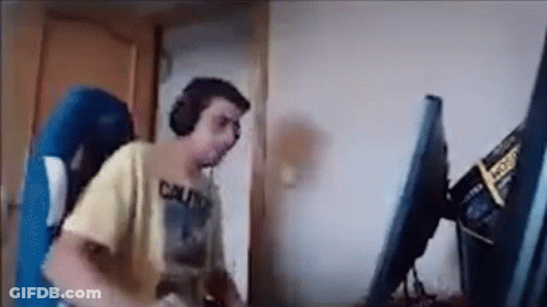 A Man Is Playing A Video Game On A Computer While Wearing Headphones . GIF