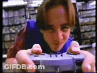 A Man Is Playing A Video Game With A Controller That Says Playstation GIF