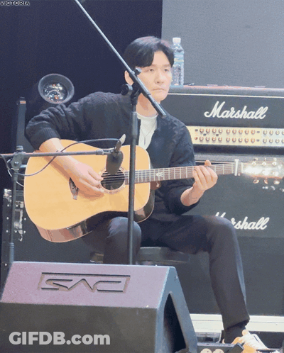 A Man Is Playing An Acoustic Guitar In Front Of A Marshall Amplifier GIF