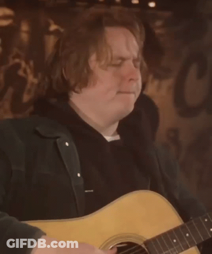 A Man Is Playing An Acoustic Guitar In Front Of A Sign That Says C GIF
