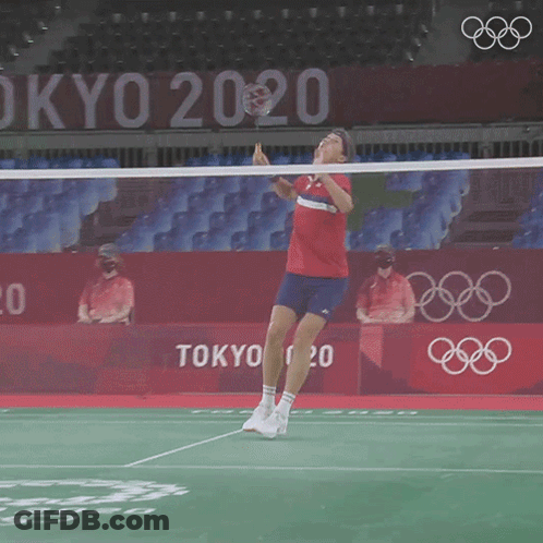 A Man Is Playing Badminton In Front Of A Tokyo 2020 Sign GIF