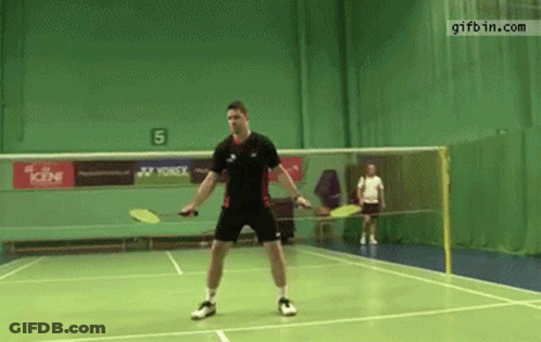 A Man Is Playing Badminton On A Court With A Yonex Advertisement On The Wall GIF