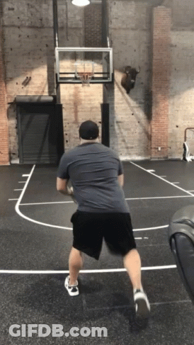 A Man Is Playing Basketball On A Court With A Bull On The Wall GIF