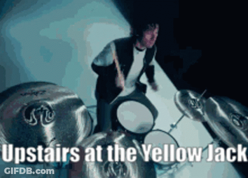 A Man Is Playing Drums With The Words Upstairs At The Yellow Jack GIF