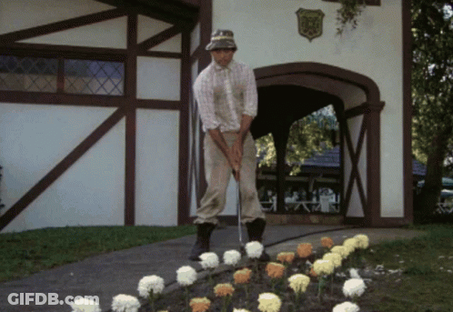 A Man Is Playing Golf In Front Of A Building With A Shield On It That Says ' Eagle ' On It GIF