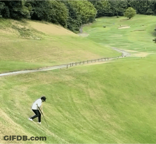 A Man Is Playing Golf On A Hill With A Fence In The Background GIF
