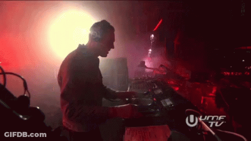 A Man Is Playing Music In A Dark Room With A Sign That Says Umf Tu GIF